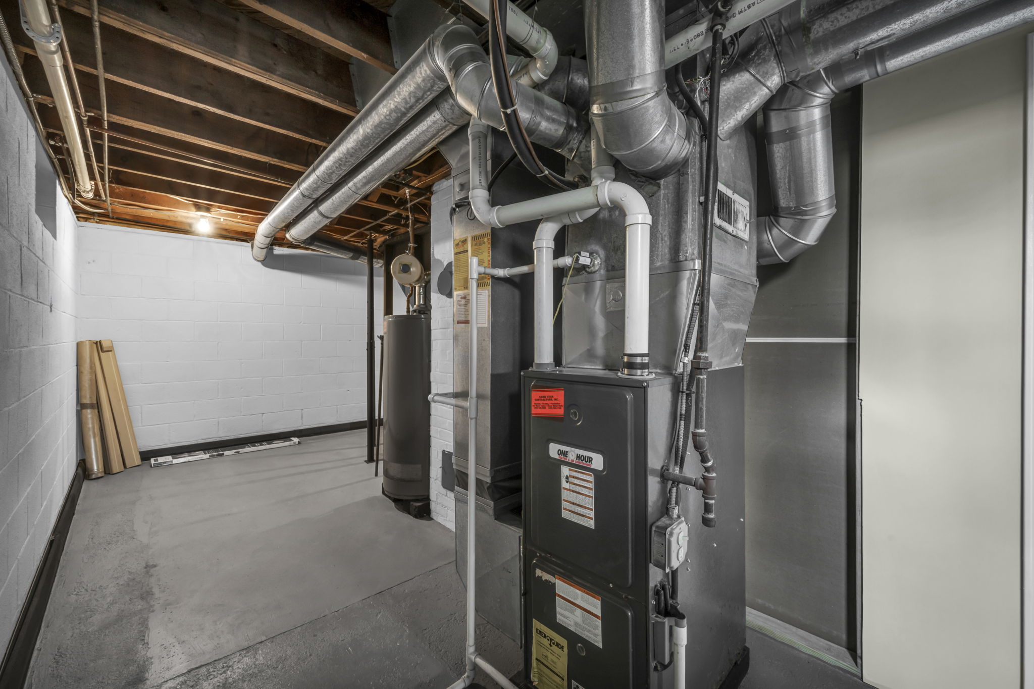 A residential basement utility room with heating equipment and ductwork