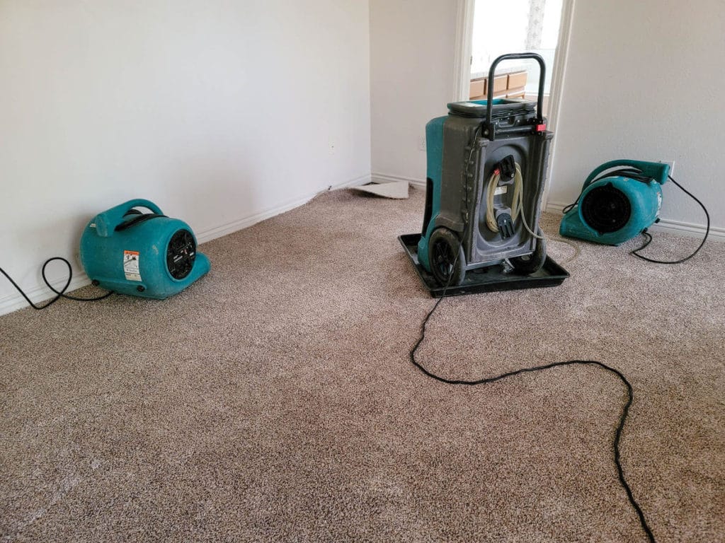 Air movers and a dehumidifier arranged indoors for structural drying